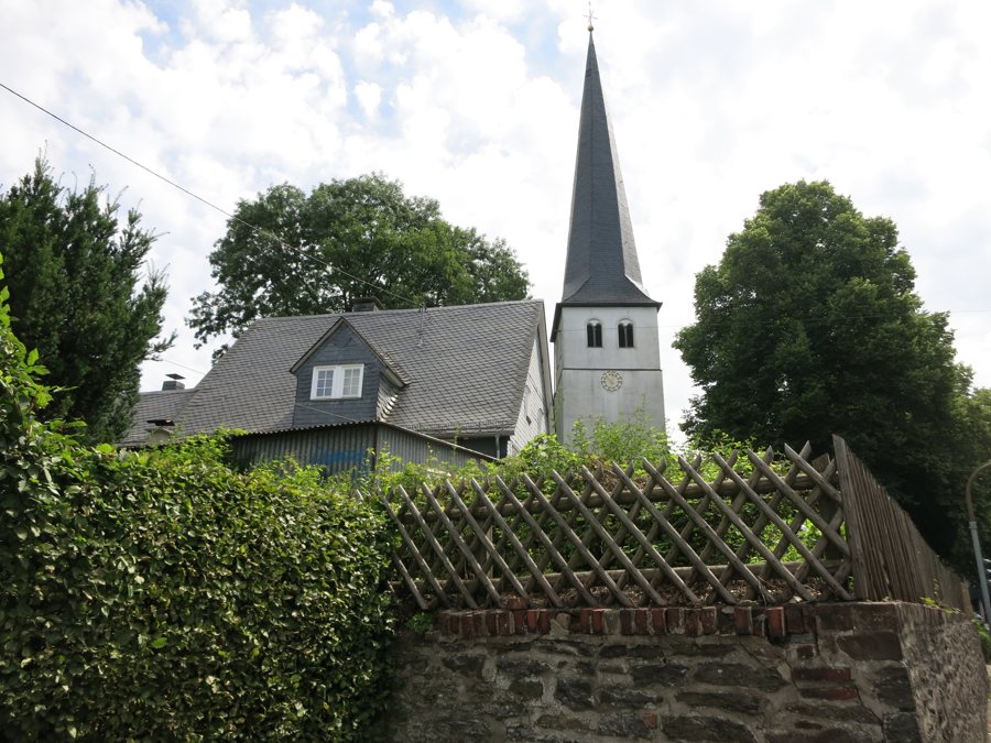 Kirchturm über einem Schieferhaus mit Holzzaun in Ferndorf.