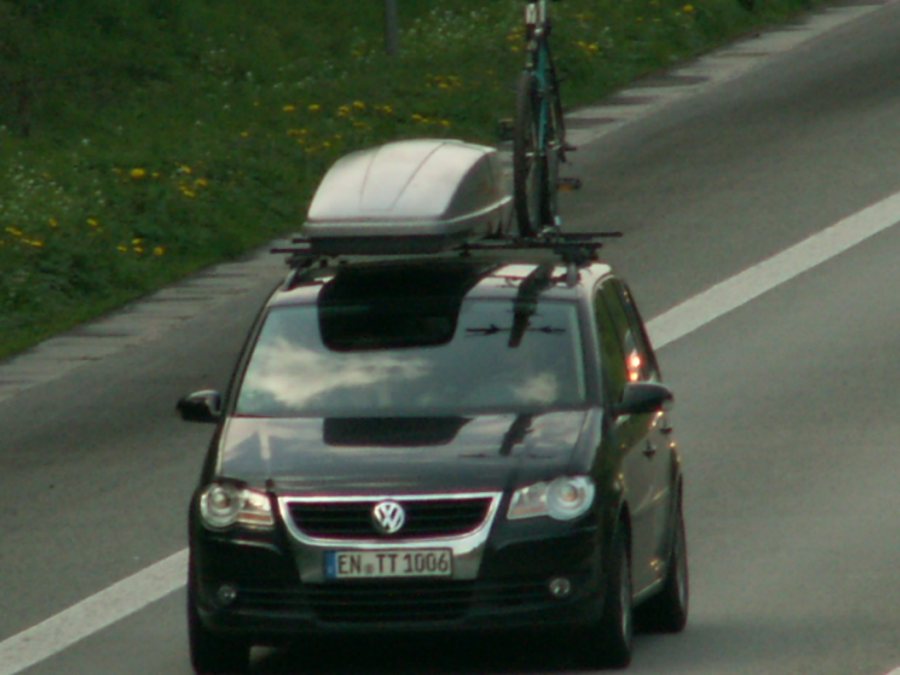 Auto mit Dachbox und Fahrradträger auf einer Straße